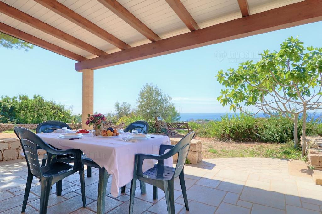 stół i krzesła na patio pod pergolą w obiekcie Case Vacanze San Gregorio by LoveSud w mieście Patù