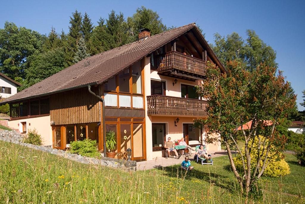 una casa grande con gente sentada fuera de ella en Ferienwohnungen Talblick 3, en Fladungen