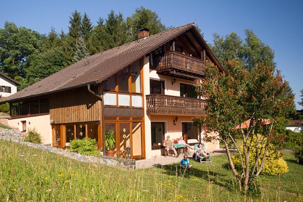 a large house with people sitting outside of it at Ferienwohnungen Talblick 3 in Fladungen