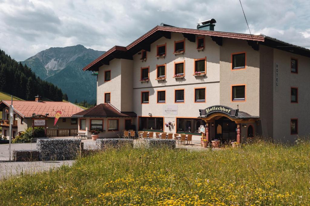 un grand bâtiment avec des montagnes en arrière-plan dans l'établissement Hotel Rotlechhof, à Berwang
