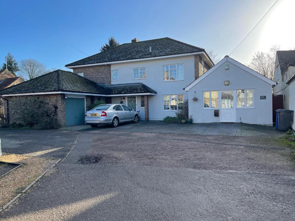 a white house with a car parked in a driveway at Silver Lodge in Mildenhall