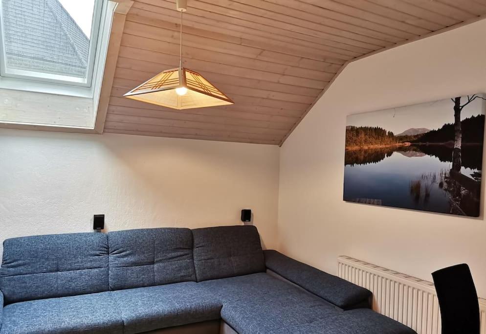 a living room with a blue couch and a light at Ferienwohnung Bergblick 