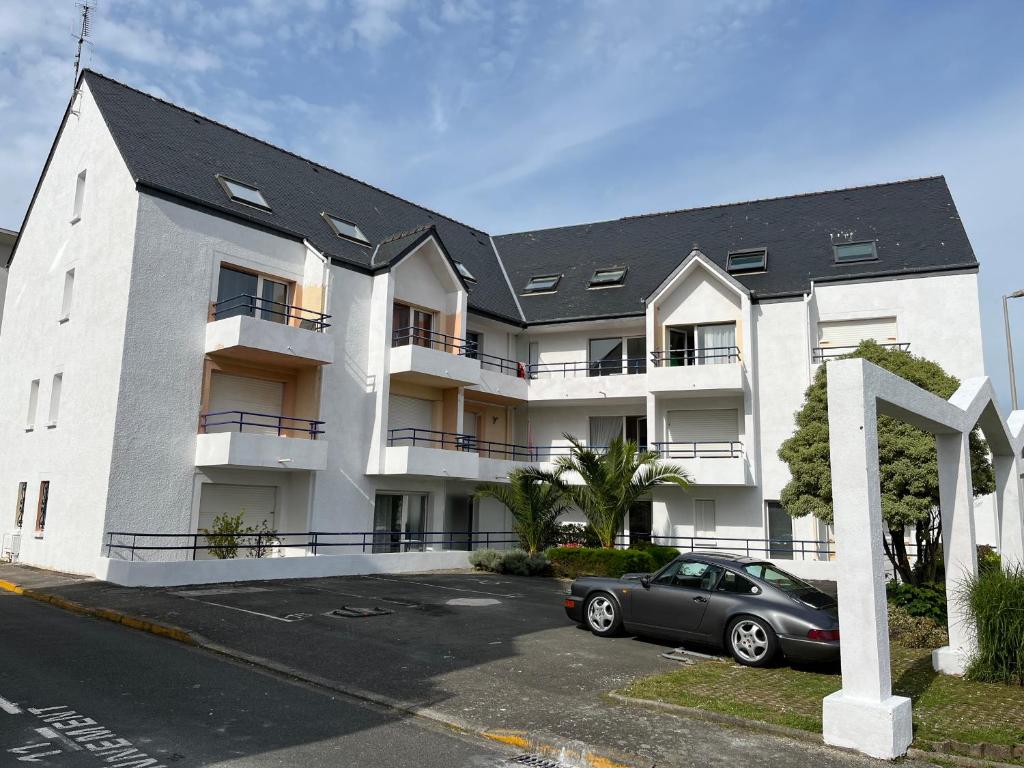 a building with a car parked in a parking lot at Duplex proche plage et centre ville in Concarneau