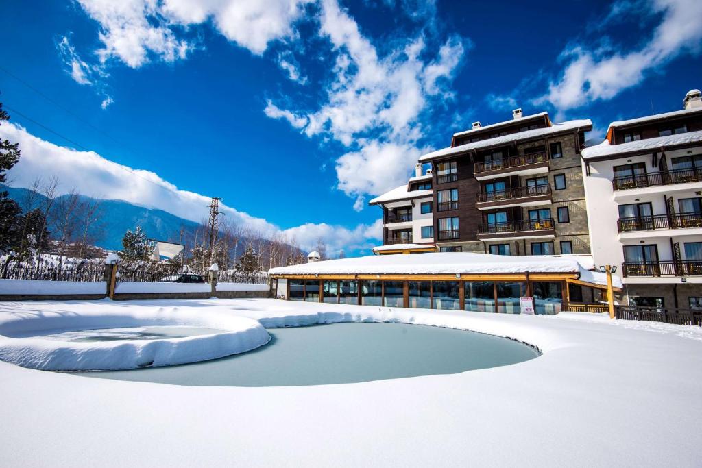 un aparcamiento cubierto de nieve frente a un edificio en The Balkan Jewel Resort, Trademark Collection by Wyndham en Bansko