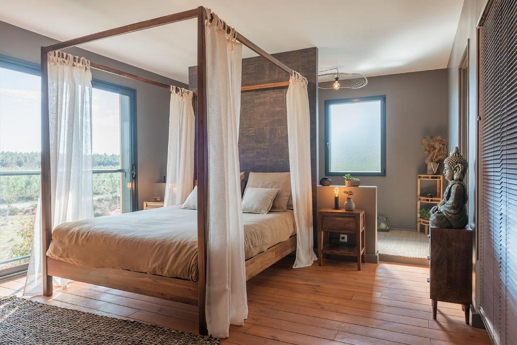 a bedroom with a four poster bed with curtains at La Grange du Coulin in Onesse-et-Laharie