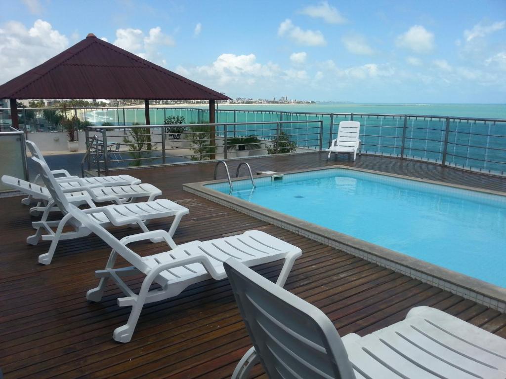 a deck with chairs and a swimming pool on a building at Manaíra Palace Residence in João Pessoa