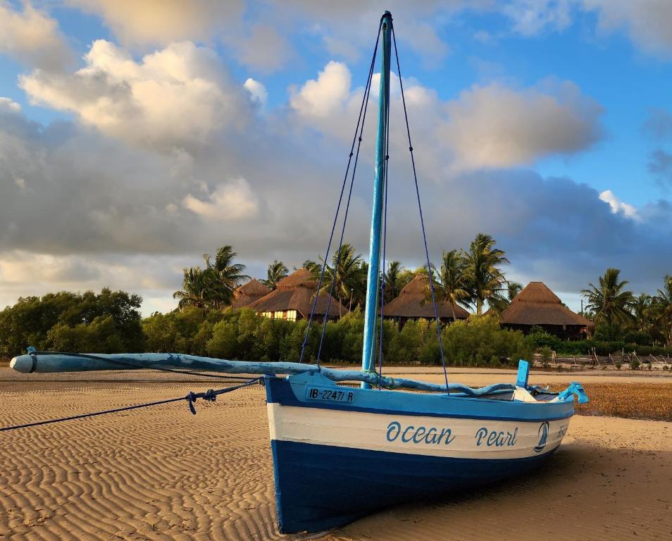 a blue and white boat sitting on the beach at Ocean Pearl Beach Lodge in Vilanculos