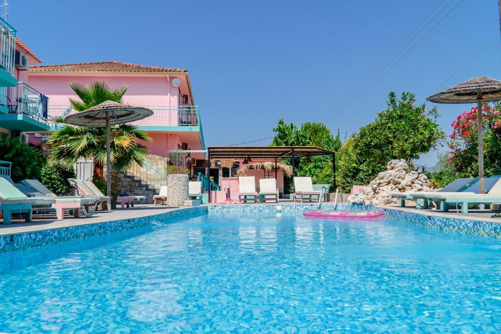 a pool at a hotel with a pink building at Maui in Laganas