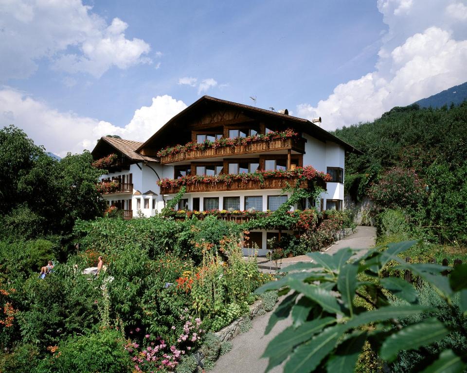 ein großes Haus mit vielen Blumen davor in der Unterkunft Hotel Garni Lichtenau in Schenna
