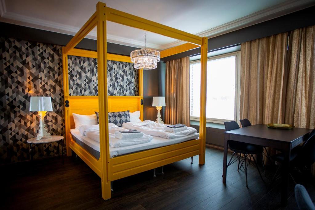 a bedroom with a yellow canopy bed and a desk at Hotelli Olof in Tornio