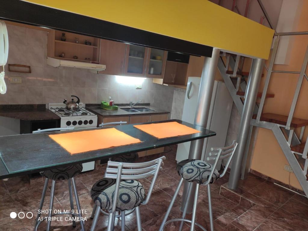 una cocina con encimera y algunos taburetes en ella en Loft Malvinas en Villa Carlos Paz