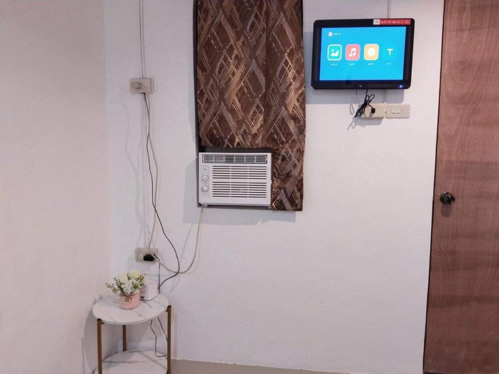 a room with a tv on the wall and a chair at Jan's Pension House - Sibulan National Highway in Sibulan