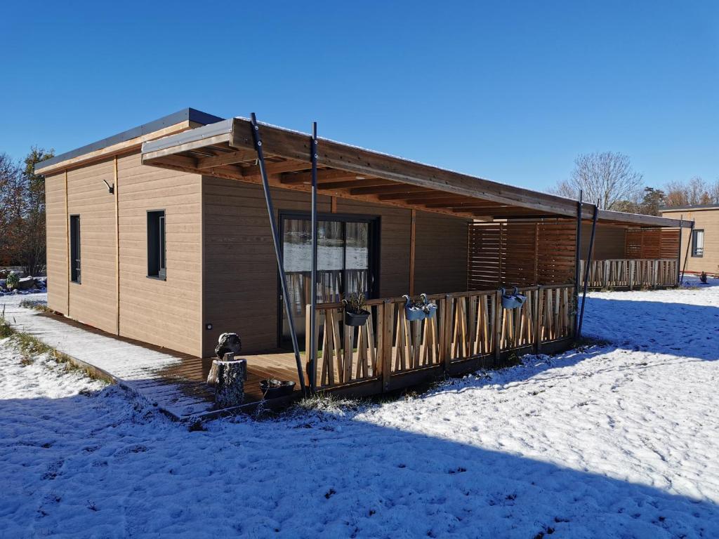 un petit bâtiment avec une terrasse couverte dans la neige dans l'établissement ACS, à Bagnols