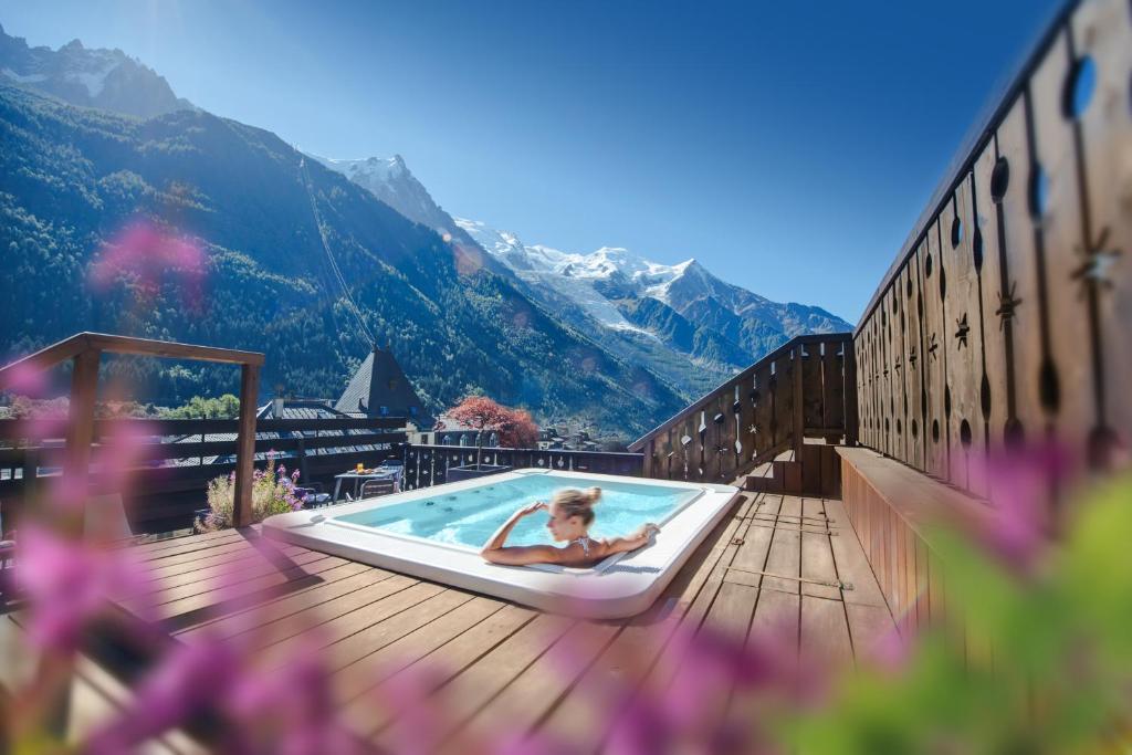 a woman laying in a pool on a deck with mountains at Park Hotel Suisse & Spa in Chamonix