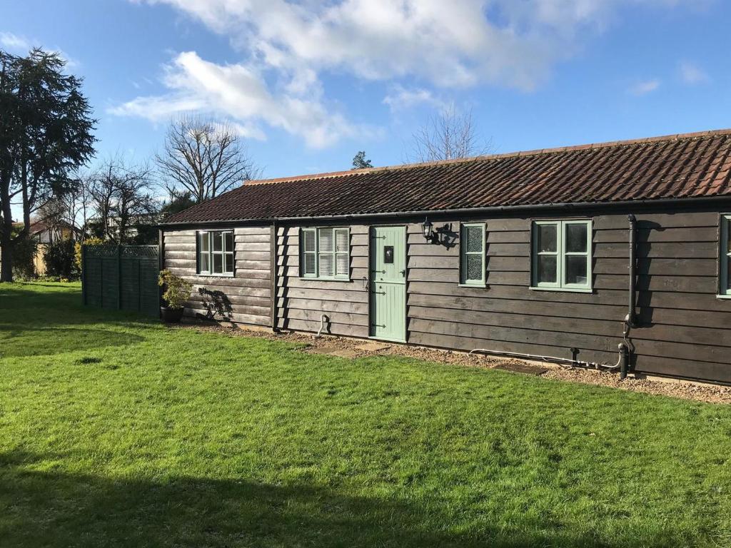 a wooden house with a green door and a yard at Tiptoe in Steeple Ashton