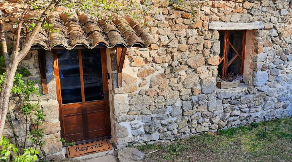 - un bâtiment en pierre avec une porte et des fenêtres en bois dans l'établissement Maison familiale chaleureuse idéalement située, à Silhac