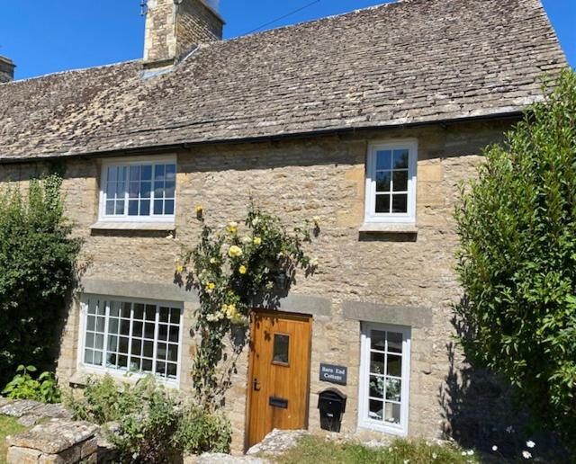 ein altes Steinhaus mit einem Blumenkranz darauf in der Unterkunft Charming Cottage, Great Rissington, Cotswolds in Great Rissington