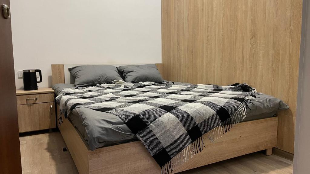 a bed with a black and white checkered blanket on it at СЕЙФ: міні-готель 24х7 in Ivano-Frankivsʼk