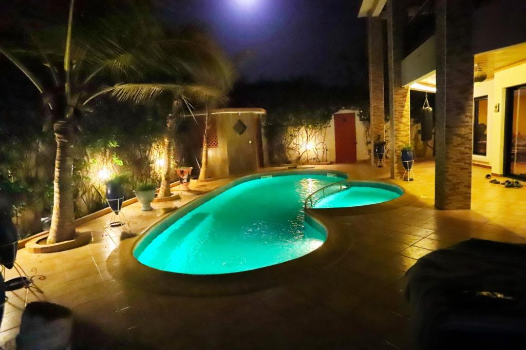 a swimming pool in a backyard at night at Chambre diambar in Saly Portudal