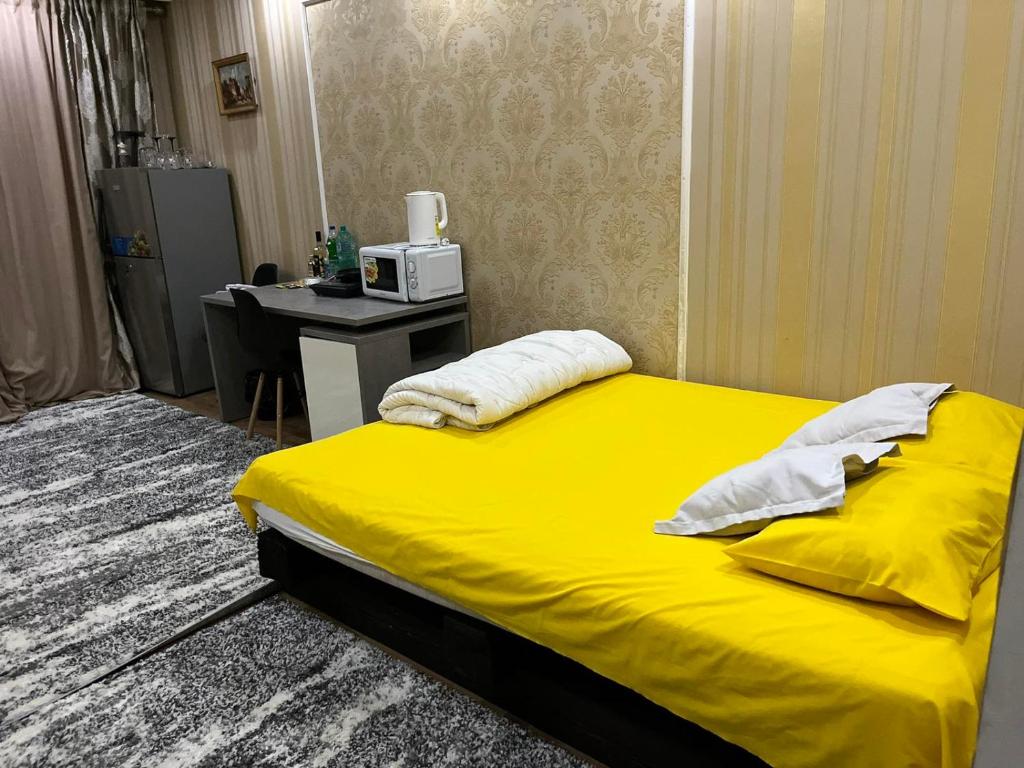 奇西瑙的住宿－Center in the center，一间卧室配有一张黄色的床和一张带微波炉的书桌