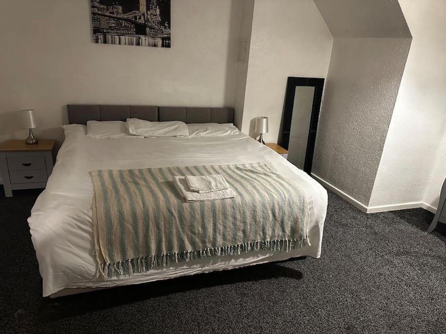 a bedroom with a bed with a blanket on it at The glorious 3 bedroom apartment with parking in Nottingham