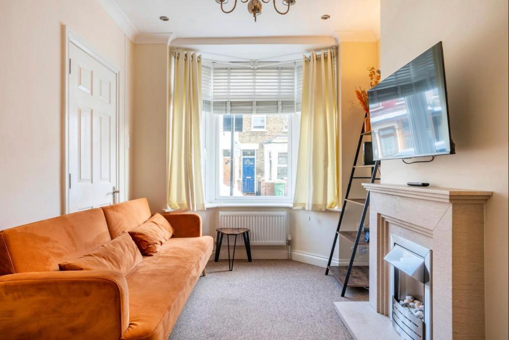 a living room with a couch and a fireplace at 2 bed terraced house with loft in Stratford London in London
