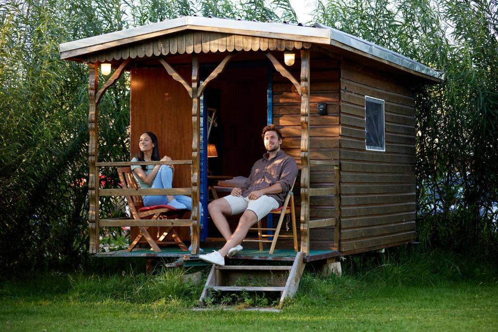 Wakenitz-Camp في Groß Sarau: رجل وامرأة يجلسون على شرفة المنزل