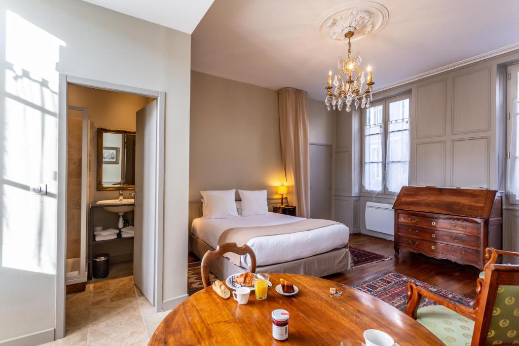 ブールジュにあるLa Maison d'Aristide - Les Univers de Panetteのベッドとテーブルが備わるホテルルームです。