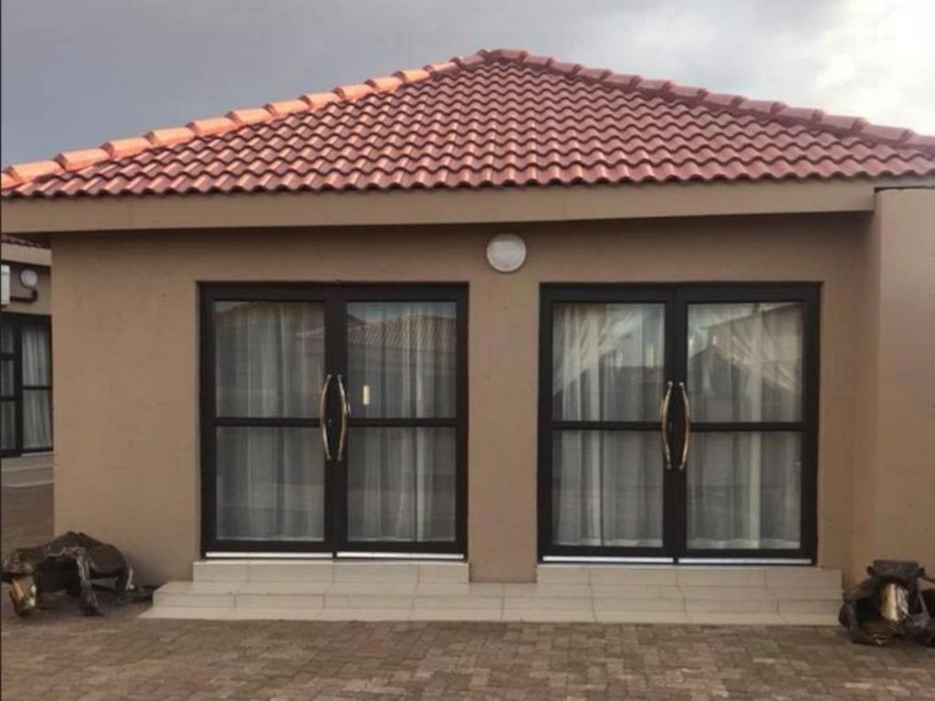 a house with three windows and a red roof at Gaediwe Guesthouse in Pudumong
