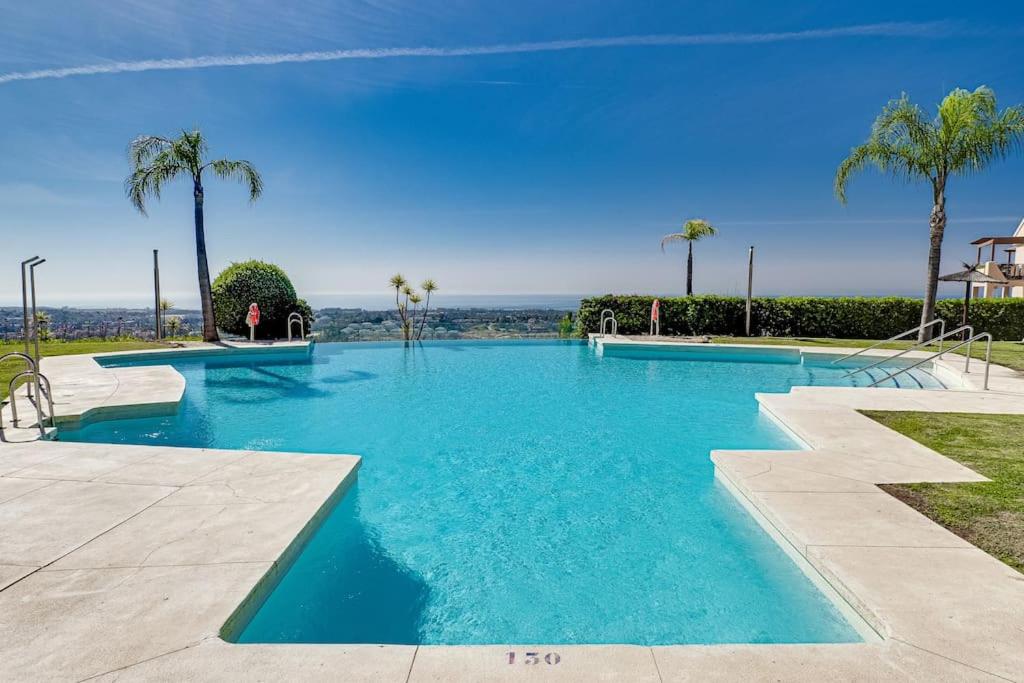 a swimming pool with blue water and palm trees at Superbe appartement avec vue mer in Estepona
