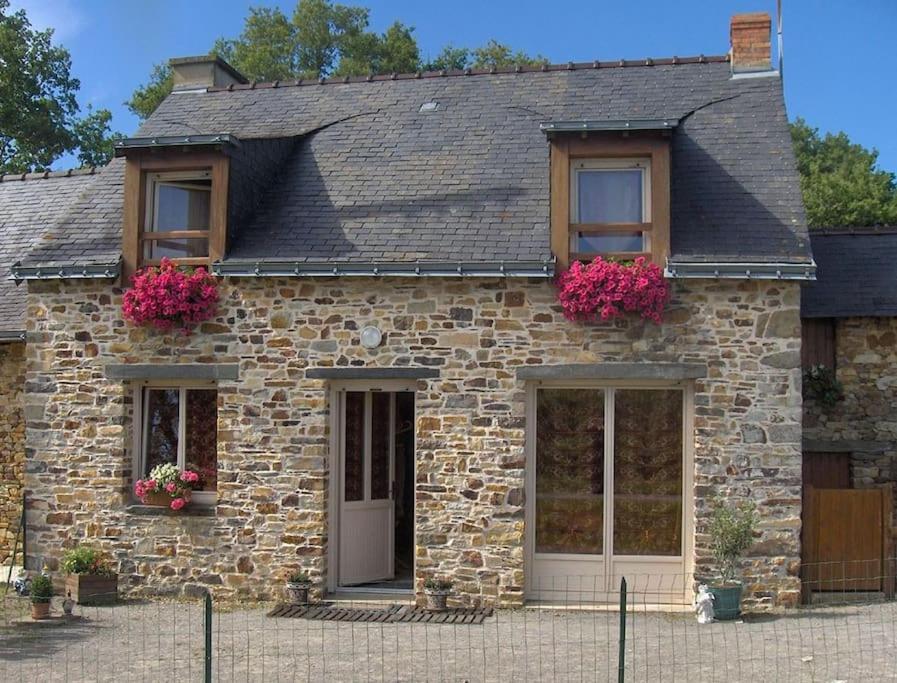 una casa de piedra con flores rosas en las ventanas en Charmante maison en campagne, en Grand-Fougeray