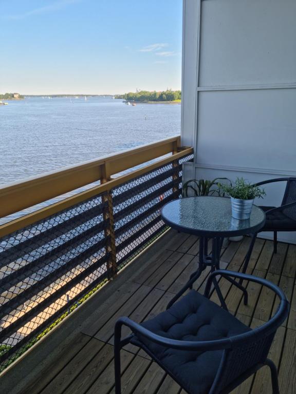 a table and chairs on a deck with a view of the water at Studio with balcony and a great sea view in Helsinki