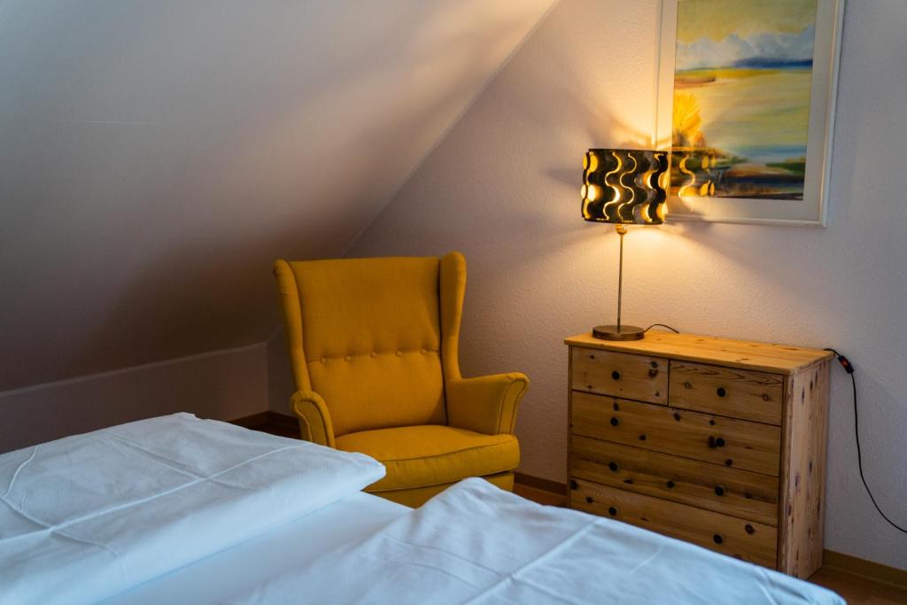 ein Schlafzimmer mit einem Bett, einem Stuhl und einer Kommode in der Unterkunft Feriendomizil & Weingut Roussel mit Restaurant "La Bonne Adresse" in Bernkastel-Kues