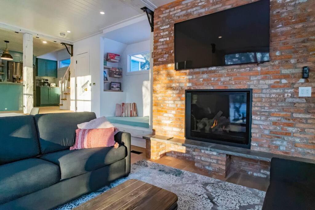 een woonkamer met een bank en een open haard bij Maison 3 chambres à coucher vue sur la montagne in Bromont