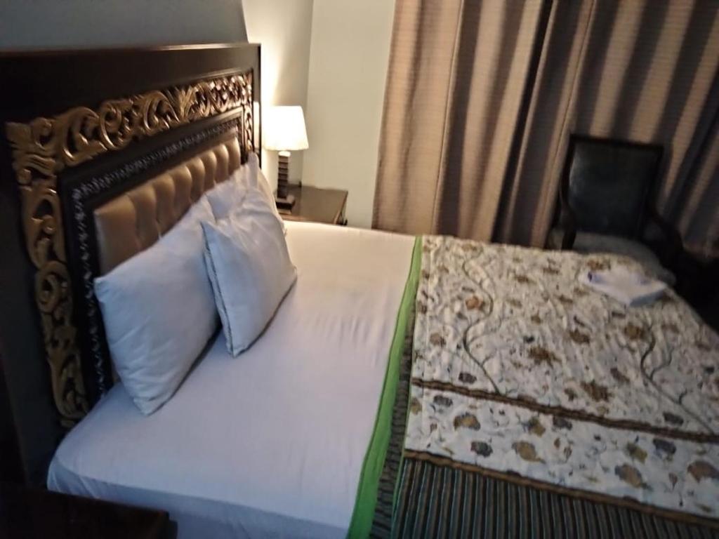 a bedroom with a bed with a pillow and a chair at Hotel Versa Appartments lodges Gulberg3 in Lahore