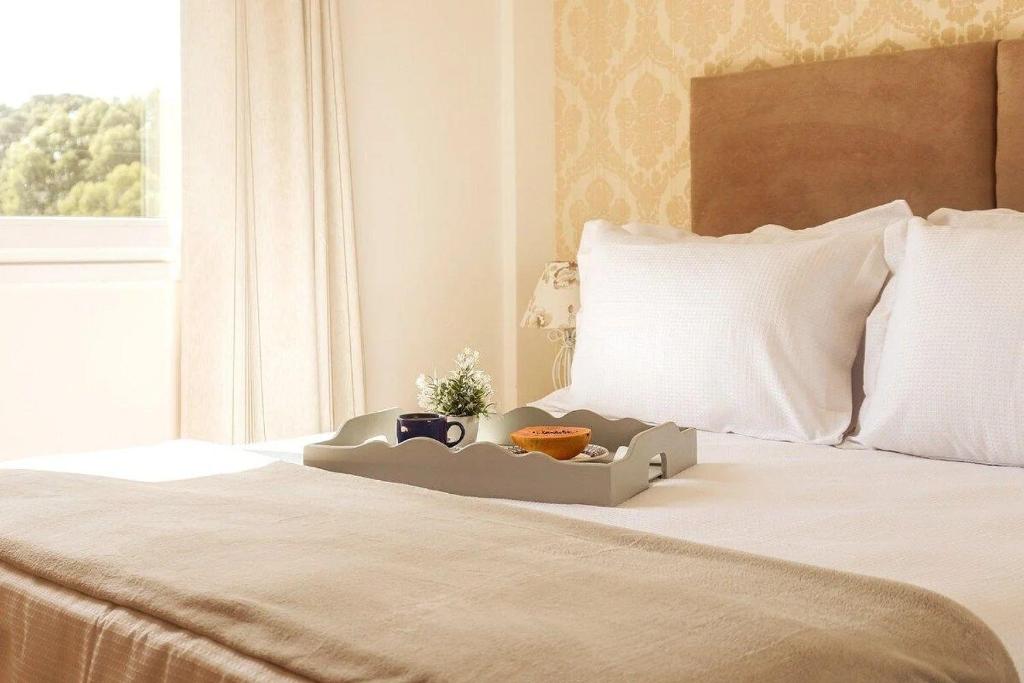 Una cama con una bandeja con dos tazas y una planta. en Apartamentos Residencial Conte 5 min da Rua Coberta by Achei Gramado, en Gramado