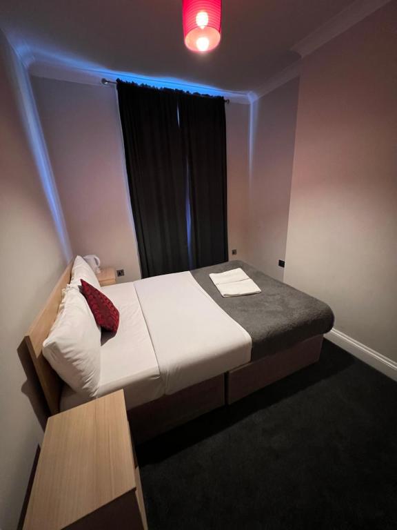 a small room with a bed with a red light at Goodwood Hotel in London