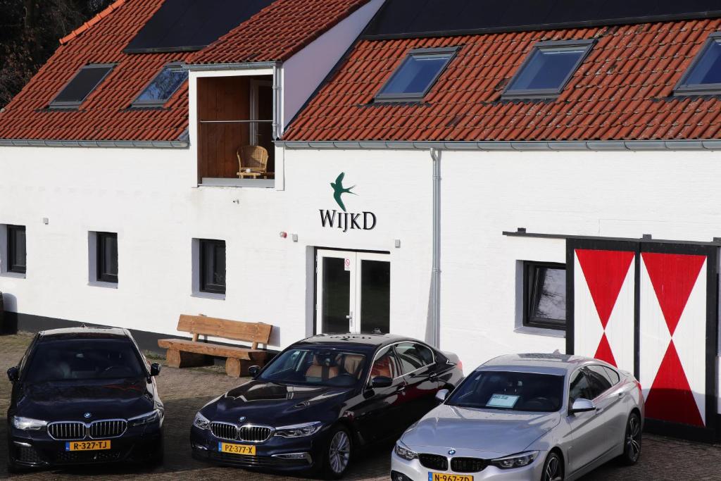 drie auto's geparkeerd voor een wit gebouw bij WijkD in Leende