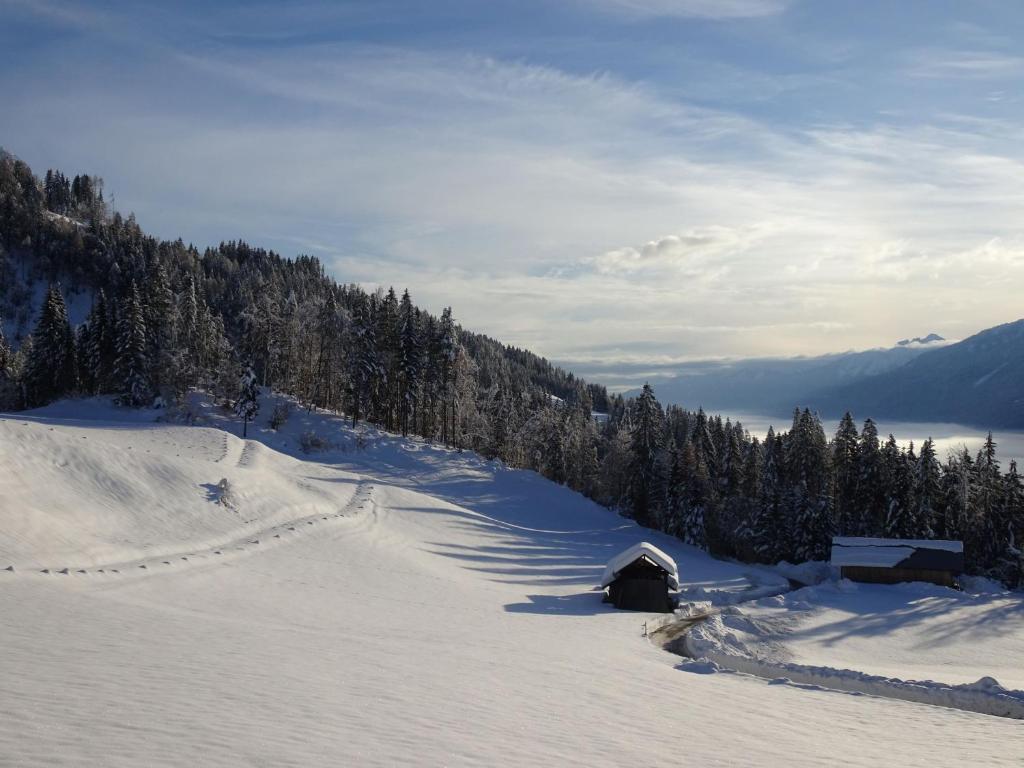 una ladera cubierta de nieve con un granero en medio de una montaña en Gasperhof, en Dellach