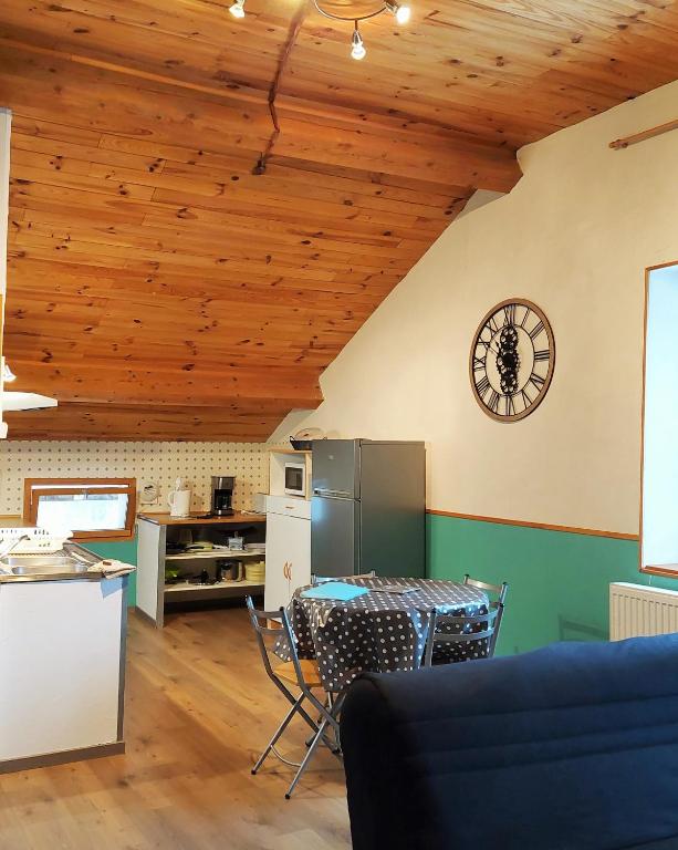 une cuisine avec une table et une horloge au mur dans l'établissement Gite Les Loges d'Arbez, à Septmoncel