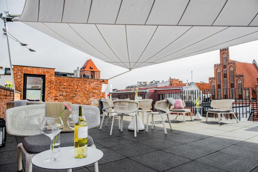eine Terrasse mit Tischen und Stühlen und einem weißen Sonnenschirm in der Unterkunft Hotel Nicolaus in Toruń