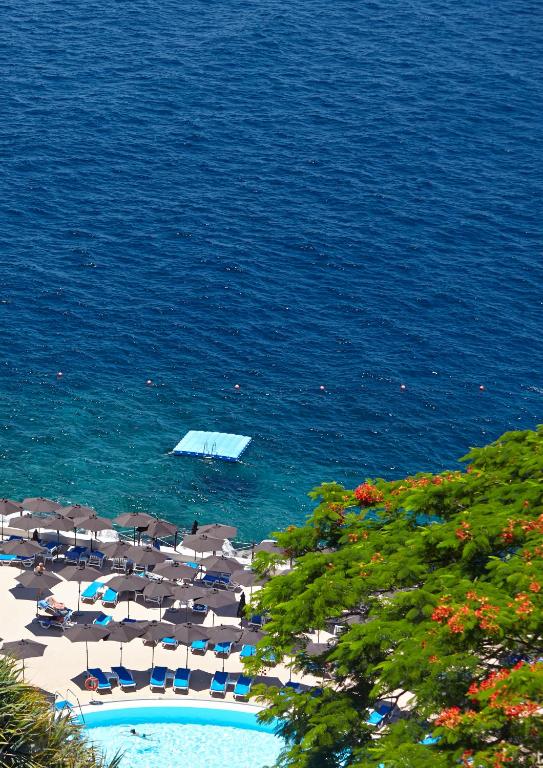 a boat in the water next to a beach at The Cliff Bay - PortoBay in Funchal