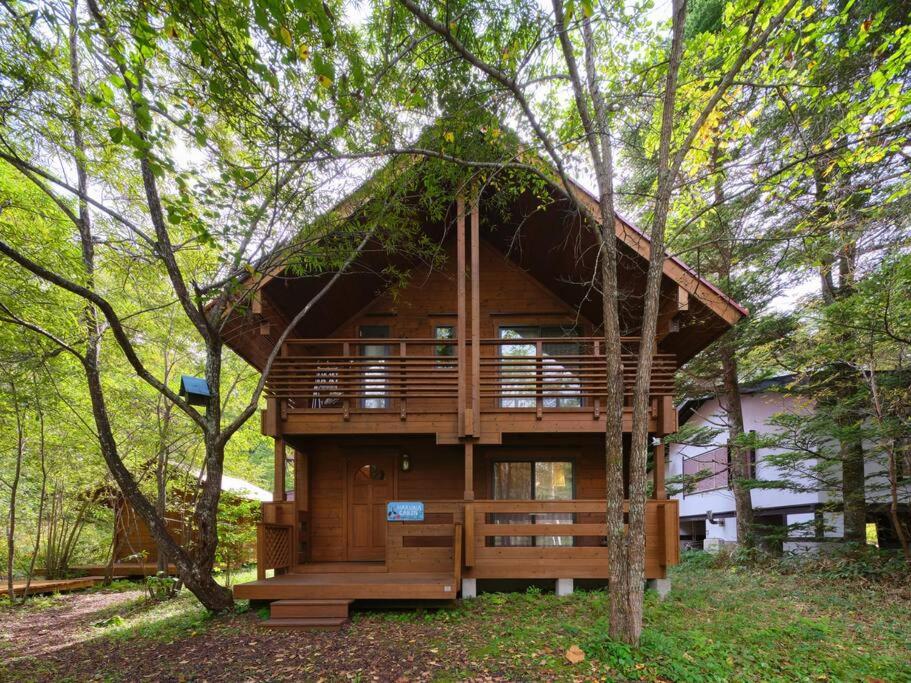 a tree house with a deck in the woods at HARUNA CABIN 森の中のログハウス 、広々ウッドデッキでBBQ、公園散策、北軽井沢観光 in Azumaiokozan