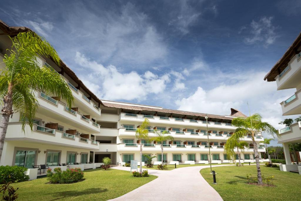una vista exterior de un gran edificio blanco con palmeras en BlueBay Grand Esmeralda-All Inclusive, en Playa del Carmen