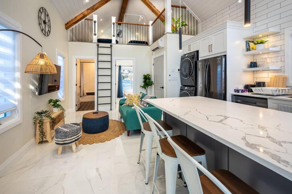a kitchen and living room with a counter and chairs at Kingsdale Designer Tiny House with Tesla Charger in Kitchener