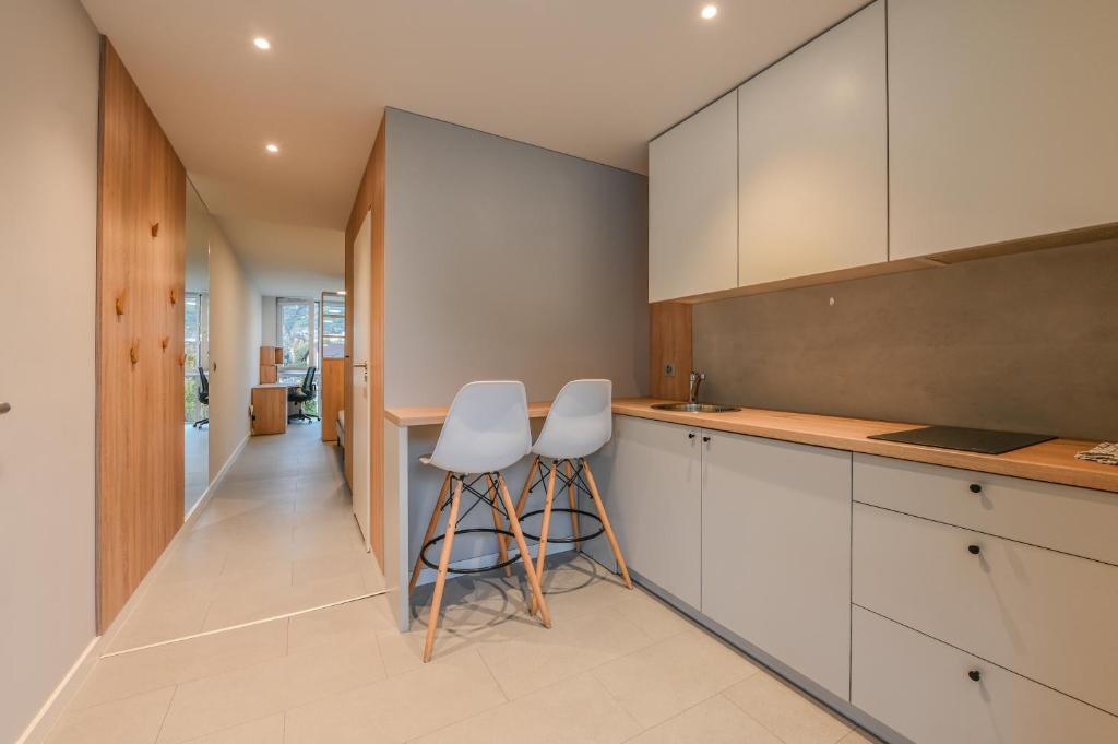 a kitchen with white cabinets and white stools at Smallville in Sion