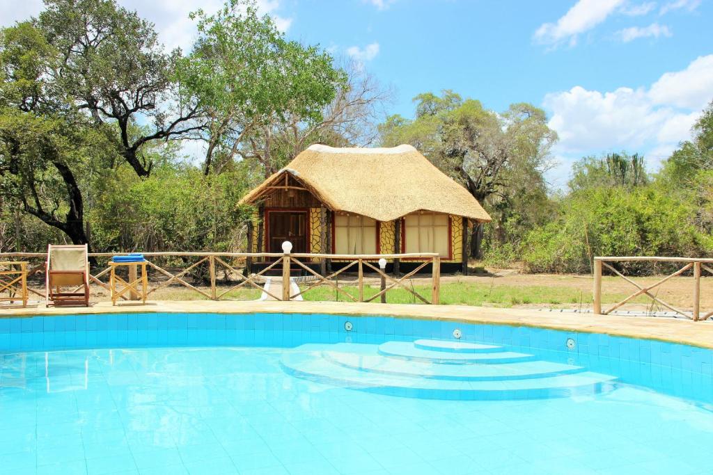 Cabaña con techo de paja y piscina frente a ella en Africa Safari Selous Nyerere national park, en Nyakisiku