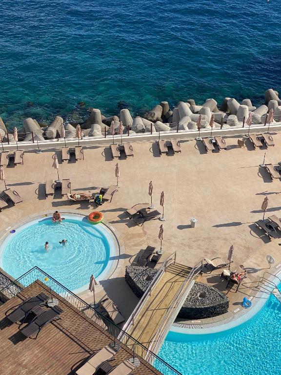 an overhead view of a swimming pool and the ocean at The Cliff Bay - PortoBay in Funchal