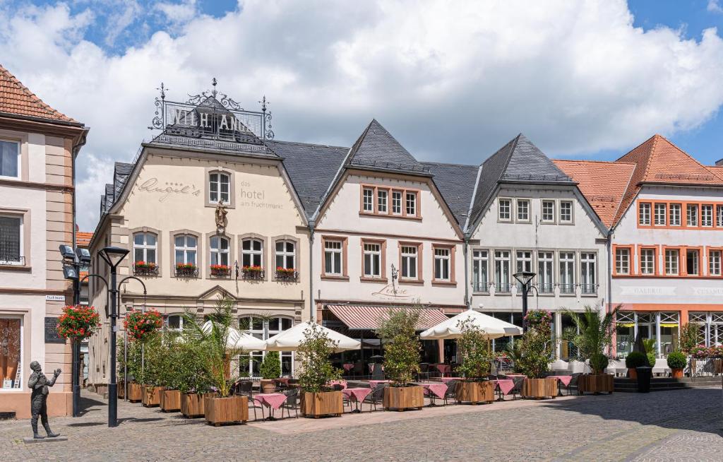 un gruppo di edifici su una strada con tavoli di Angel's - das hotel am fruchtmarkt a Sankt Wendel