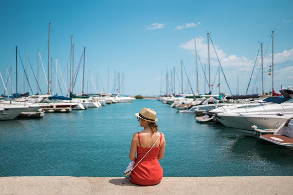 uma mulher sentada num parapeito a olhar para uma marina em Imagine972 Martinique Bateau Hotel à Quai le Marin 3 Cabines 3 Salles de bains 6 pers maxi em Le Marin